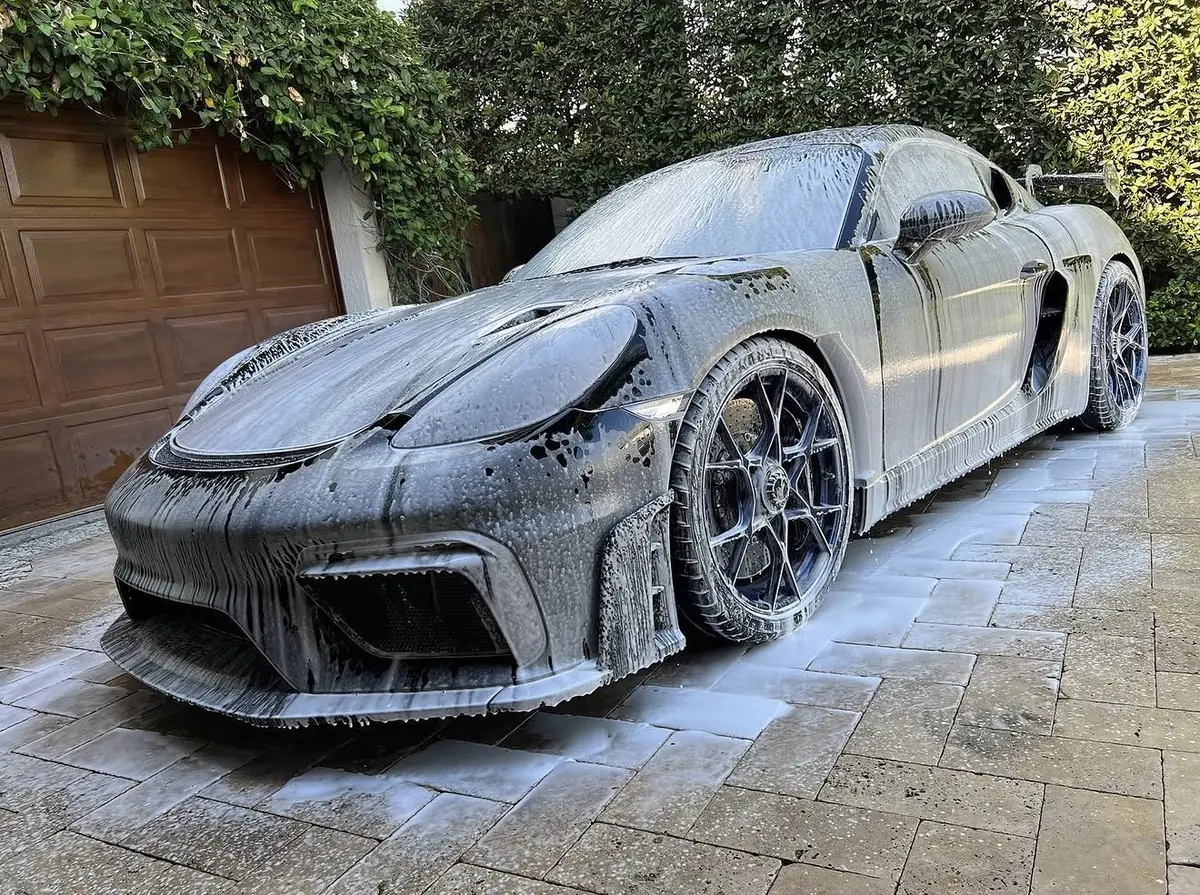 Porsche covered in wash foam on a driveway